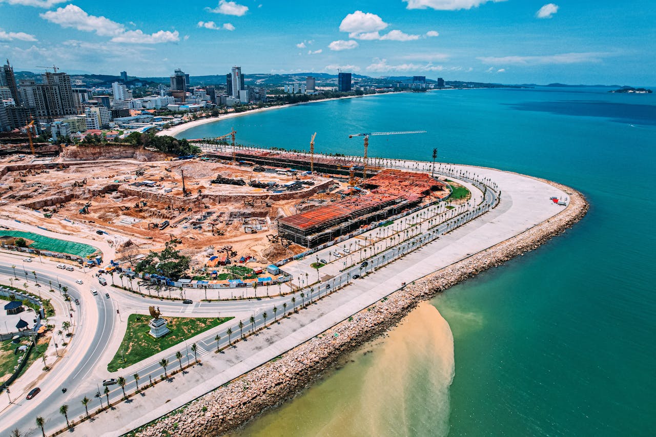 Aerial photo showcasing a coastal construction site with urban cityscape, taken in bright daylight.