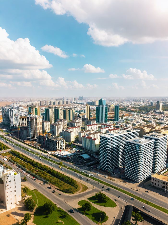 A stunning aerial view showcasing modern buildings in an Iraqi city under a vibrant blue sky.